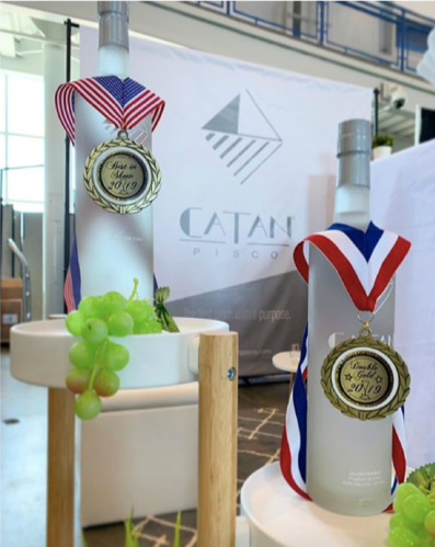 Bottles of Catan Pisco with gold medals placed onto them.