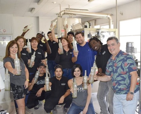 Group photo of people posing with bottles of Catan Pisco